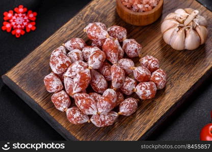 Spanish Fuet sausage slices, on a dark concrete background. Delicious dry sausage with walnuts on a christmas table. Dry cured fuet sausage on a dark background