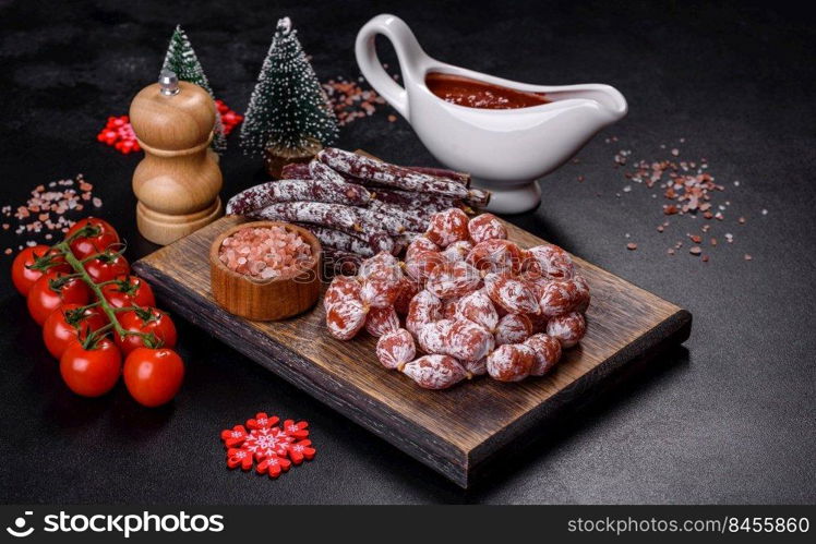 Spanish Fuet sausage slices, on a dark concrete background. Delicious dry sausage with walnuts on a christmas table. Dry cured fuet sausage on a dark background