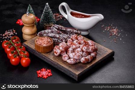 Spanish Fuet sausage slices, on a dark concrete background. Delicious dry sausage with walnuts on a christmas table. Dry cured fuet sausage on a dark background