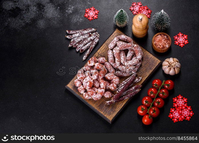 Spanish Fuet sausage slices, on a dark concrete background. Delicious dry sausage with walnuts on a christmas table. Dry cured fuet sausage on a dark background