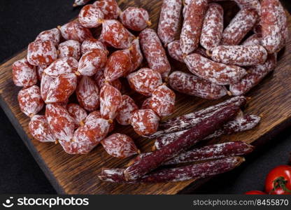 Spanish Fuet sausage slices, on a dark concrete background. Delicious dry sausage with walnuts on a concrete table. Dry cured fuet sausage on a dark background