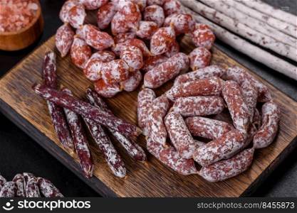Spanish Fuet sausage slices, on a dark concrete background. Delicious dry sausage with walnuts on a concrete table. Dry cured fuet sausage on a dark background