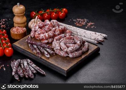 Spanish Fuet sausage slices, on a dark concrete background. Delicious dry sausage with walnuts on a concrete table. Dry cured fuet sausage on a dark background