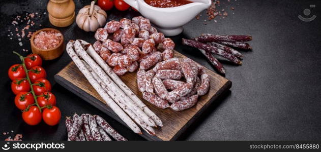 Spanish Fuet sausage slices, on a dark concrete background. Delicious dry sausage with walnuts on a concrete table. Dry cured fuet sausage on a dark background