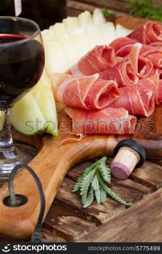 spanish tapas - slices of cured pork ham jamon with melon and wine