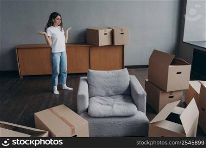 Spanish woman feels hard to move alone. Young lady is exhausted with boxes packing. Pretty girl in new apartment. Annoyed young lady has problem. Delivery service ordering concept.. Spanish woman feels hard to move alone exhausted with boxes packing. Delivery service ordering.
