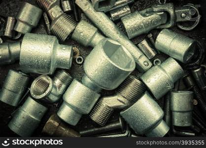 Spanner wrench heads, nuts and bolts on a dark scratched metal background. Toned.