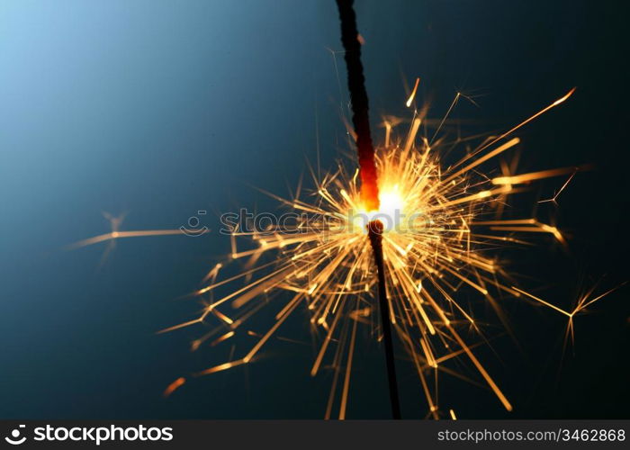 sparkler fire on blue macro background close up