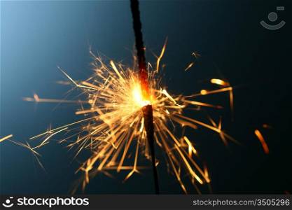 sparkler fire on blue macro background close up