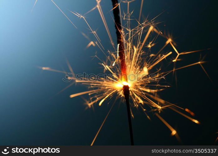 sparkler fire on blue macro background close up