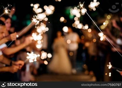 sparklers at the wedding, a couple of newlyweds on the background