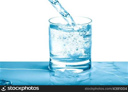 Sparkling water pouring into glass over bright background. Cold drink. Blue colored picture