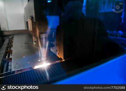 Sparks fly out machine head for metal processing laser metal on metallurgical plant background. Manufacturing finished parts for automotive production concept. High quality photo. Sparks fly out machine head for metal processing laser metal on metallurgical plant background. Manufacturing finished parts for automotive production concept