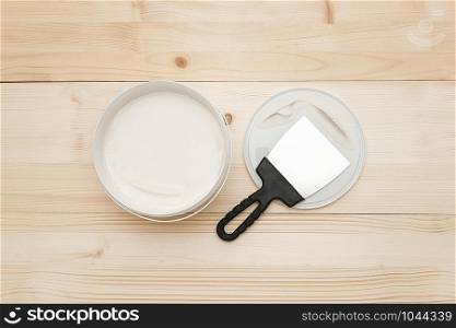 Spatula and a bucket of white putty on wooden boards. Top view Copy space.. Spatula and a bucket of white putty on wooden boards. Top view Copy space