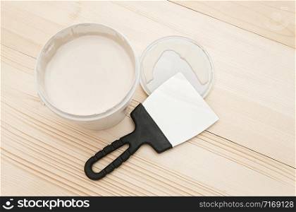 Spatula and a bucket of white putty on wooden boards. Top view Copy space.. Spatula and a bucket of white putty on wooden boards. Top view Copy space