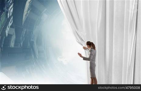 Speaker on stage. Young businesswoman opening stage curtain to another reality