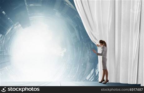 Speaker on stage. Young businesswoman opening stage curtain to another reality