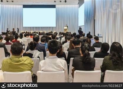 Speakers on the stage with Rear view of Audience in the conference hall or seminar meeting, business and education about investment concept