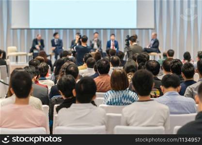 Speakers on the stage with Rear view of Audience in the conference hall or seminar meeting, business and education about investment concept