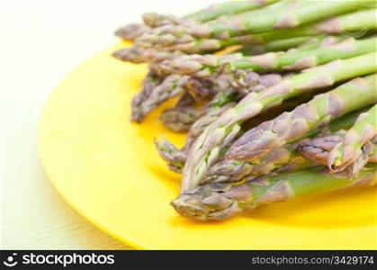 Spears of Fresh Uncooked Asparagus on Yellow Plate - Shallow Depth of Field