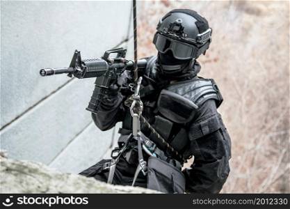 Spec ops police officer SWAT during rope exercises with weapons. tactical rappeling