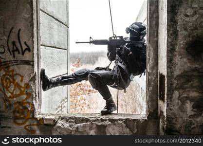 Spec ops police officer SWAT during rope exercises with weapons. tactical rappeling