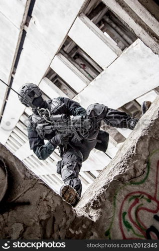 Spec ops police officer SWAT during rope exercises with weapons. tactical rappeling