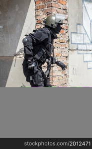 Spec ops soldier in black uniform and face mask aiming his pistol