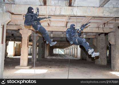 Special forces operators during assault rappeling with weapons . assault rappeling
