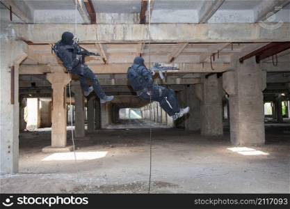 Special forces operators during assault rappeling with weapons . assault rappeling
