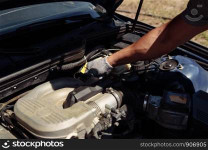 Specialist auto mechanic in the car service, checks the car, engine, engine, carburetor. Concept: repair of machines, fault diagnosis, repair specialist, technical maintenance. Mechanic standing in front of the open hood and repairing the car