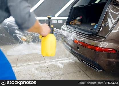Specialists applies car protection film on rear bumper. Installation of coating that protects the paint of automobile from scratches. New vehicle in garage, tuning. Specialists applies car protection film on bumper