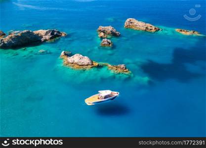 Speed boat on blue sea at sunrise in summer. Aerial view of motorboat on sea bay, rocks in clear azure water. Tropical landscape with yacht, stones. Top view from drone. Travel in Oludeniz, Turkey