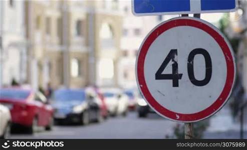 Speed limit 40 km hour road sign in the city street on summer day. The focus point is on the speed limit sign on the right. Blurred background of traffic in the city street