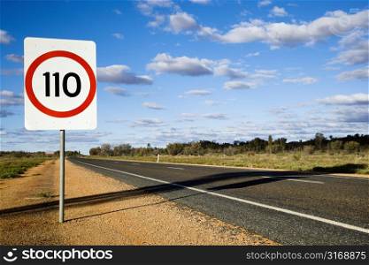 Speed limit kilometer per hour road sign by road in rural Australia.