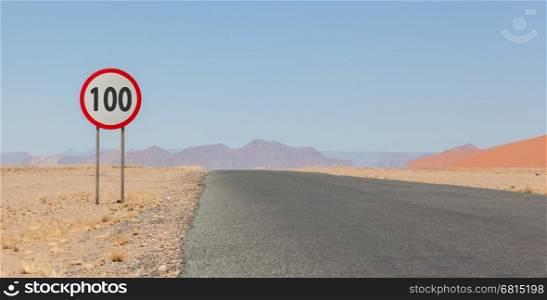 Speed limit sign at a desert road in Namibia, speed limit of 100 kph or mph, selective focus