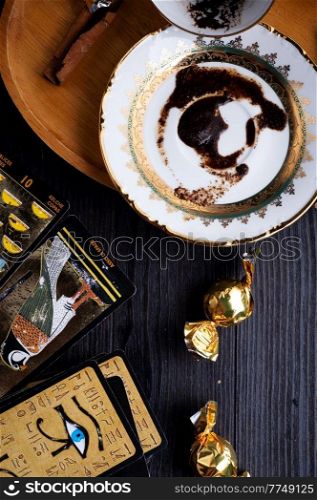 spelling coffee plate  with  coffee grounds and Tarot cards served at dark wooden table. devination concept 