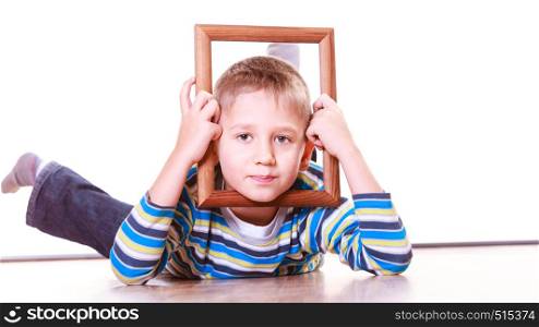 Spending free time and have fun. Playful little boy play with empty picture frame show face lie on floor.. Boy lie on floor and play with frame.