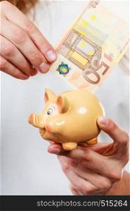 Spending money concept. Male hands with piggybank and euro banknote cash. Savings.. Male hands with banknote and piggybank