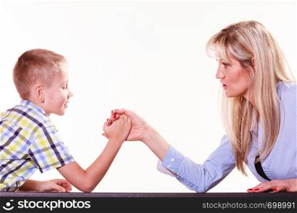 Spending time with family fun and family bonds. Mother and son arm wrestle and have fun indoors.. Mother and son arm wrestle sit at table.