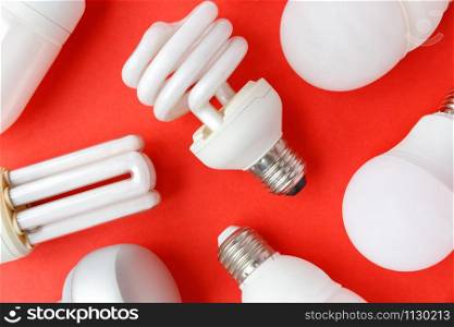 Spent incandescent halogen, cfi fluorescent, led, lumens light and energy saving bulbs tube, red background. Lamps containing mercury - extremely hazardous waste, very toxic to human health. Close up.