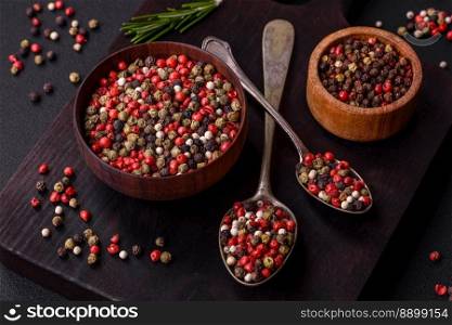Spice allspice of different colors pink, white, green not ground in a wooden saucer on a dark concrete background