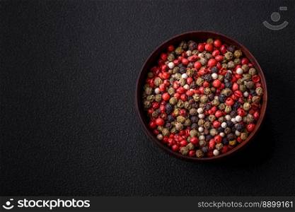 Spice allspice of different colors pink, white, green not ground in a wooden saucer on a dark concrete background