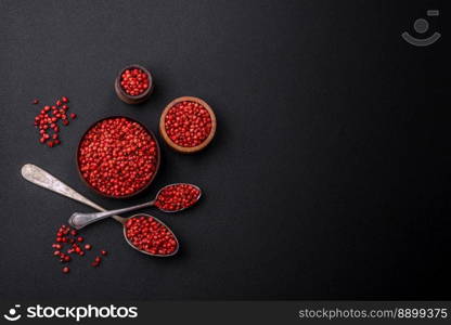 Spice, allspice peas in red or pink color in a wooden bowl on a black concrete background. Asian cuisine