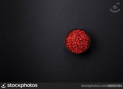 Spice, allspice peas in red or pink color in a wooden bowl on a black concrete background. Asian cuisine