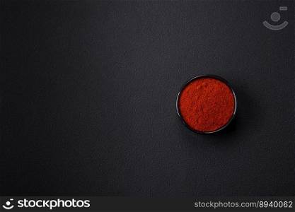 Spice smoked paprika in the form of powder in bowls and spoons on a dark concrete background. Asian cuisine ingredients