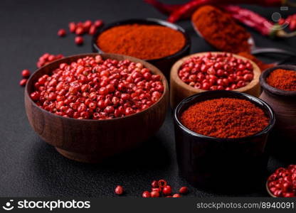 Spice smoked paprika in the form of powder in bowls and spoons on a dark concrete background. Asian cuisine ingredients