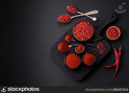 Spice smoked paprika in the form of powder in bowls and spoons on a dark concrete background. Asian cuisine ingredients