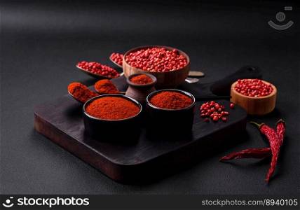 Spice smoked paprika in the form of powder in bowls and spoons on a dark concrete background. Asian cuisine ingredients