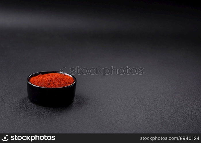 Spice smoked paprika in the form of powder in bowls and spoons on a dark concrete background. Asian cuisine ingredients